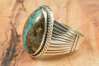 Genuine Sunnyside Turquoise set in Sterling Silver Ring. The matrix on this rare stone is outstanding. The Sunnyside mine is located in northern Nevada near the town of Tuscarora in the Tuscarora mountain range. The mine is no longer in operation as it has become part of a gold mining operation and a privately owned ranch. The Sunnyside mine was mined mostly in the 70's. You won't find much of this great turquoise around anymore except for old stashes. Created by Navajo Artist Larson Lee. 
